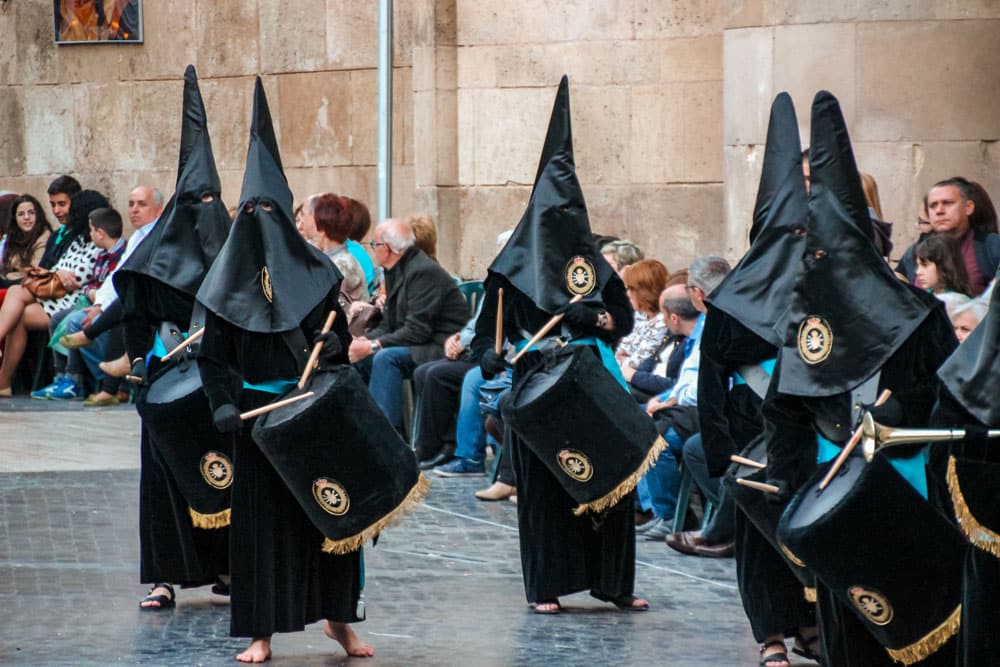 Barefoot hooded penitents play drumms during the parade