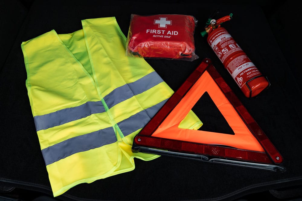 Car emergency kit: first aid kit, reflective triangle, safety vest and fire extinguisher.