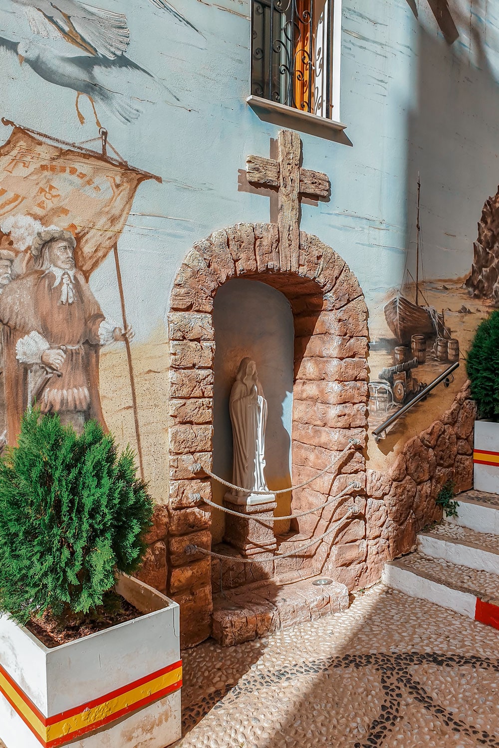A beautiful wall painting and a holy statue built into the wall.