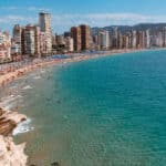 Long sandy beach in Benidorm with high buildings.