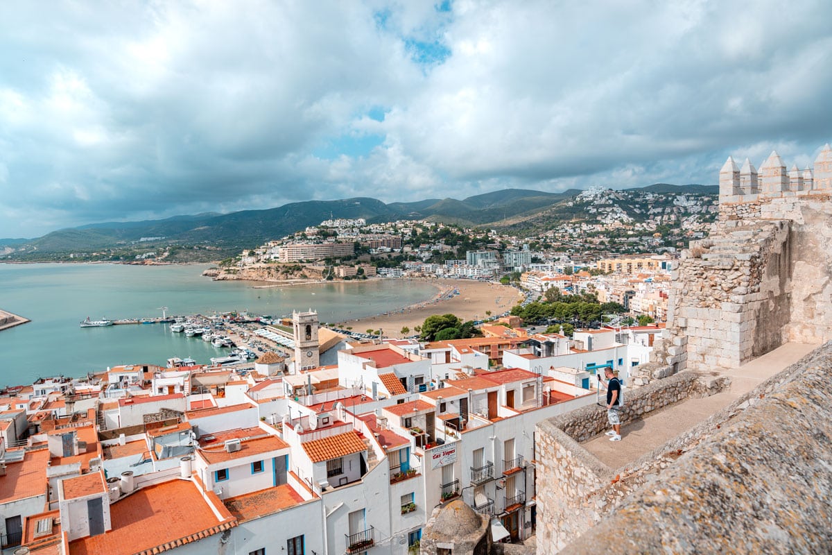 Peniscola ancient stone walls surrounded with white buildings and a harbor.