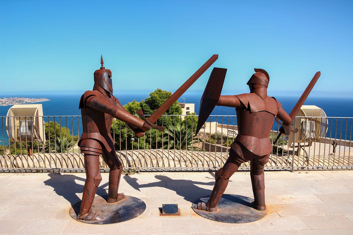Metal statues of knights fighting with swords.