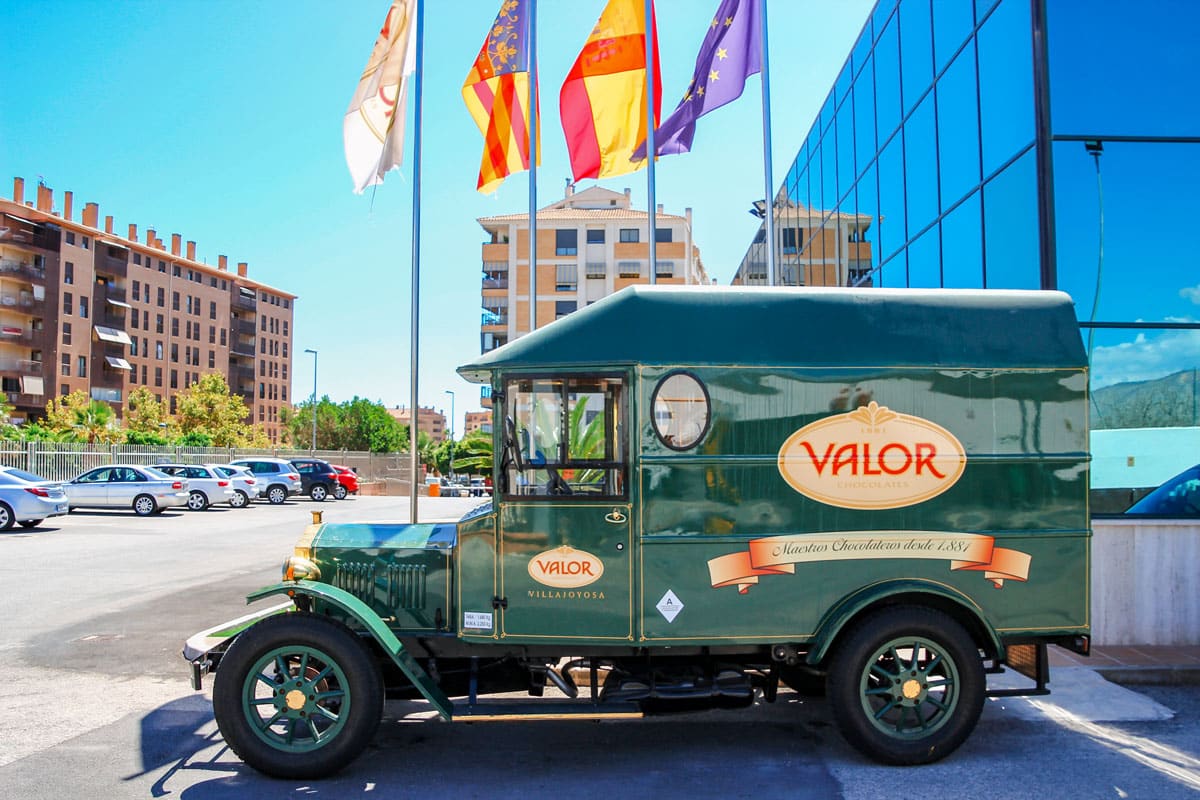 Vintage green truck with the logo of Valor chocolates parked outside the factory.