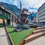 A surreal sculpture of a melting clock by Salvador Dali in a public square in Andorra la Vella, with mountains in the background.