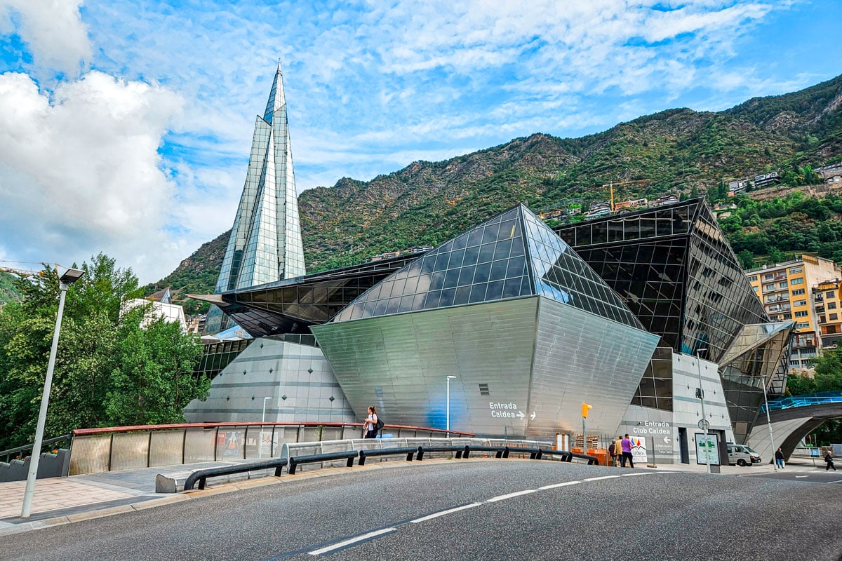 Modern architectural building with a tall glass spire, part of a large spa and wellness center located in Andorra.