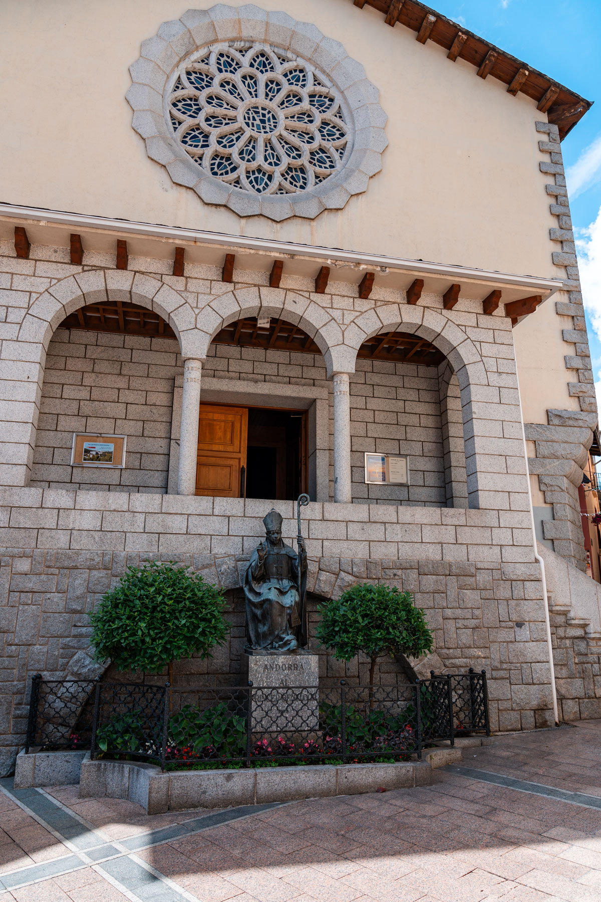 Church facade with rose window and bishop statue.