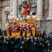 Holy Week procession with float and black-robed nazarenos in front of Murcia Cathedral.