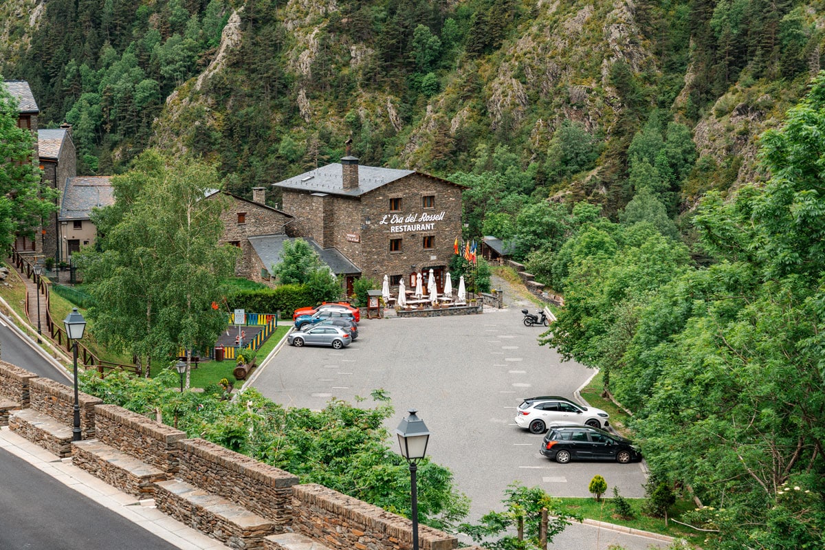 Mountain stop in Andorra with parking area beside a stone restaurant.