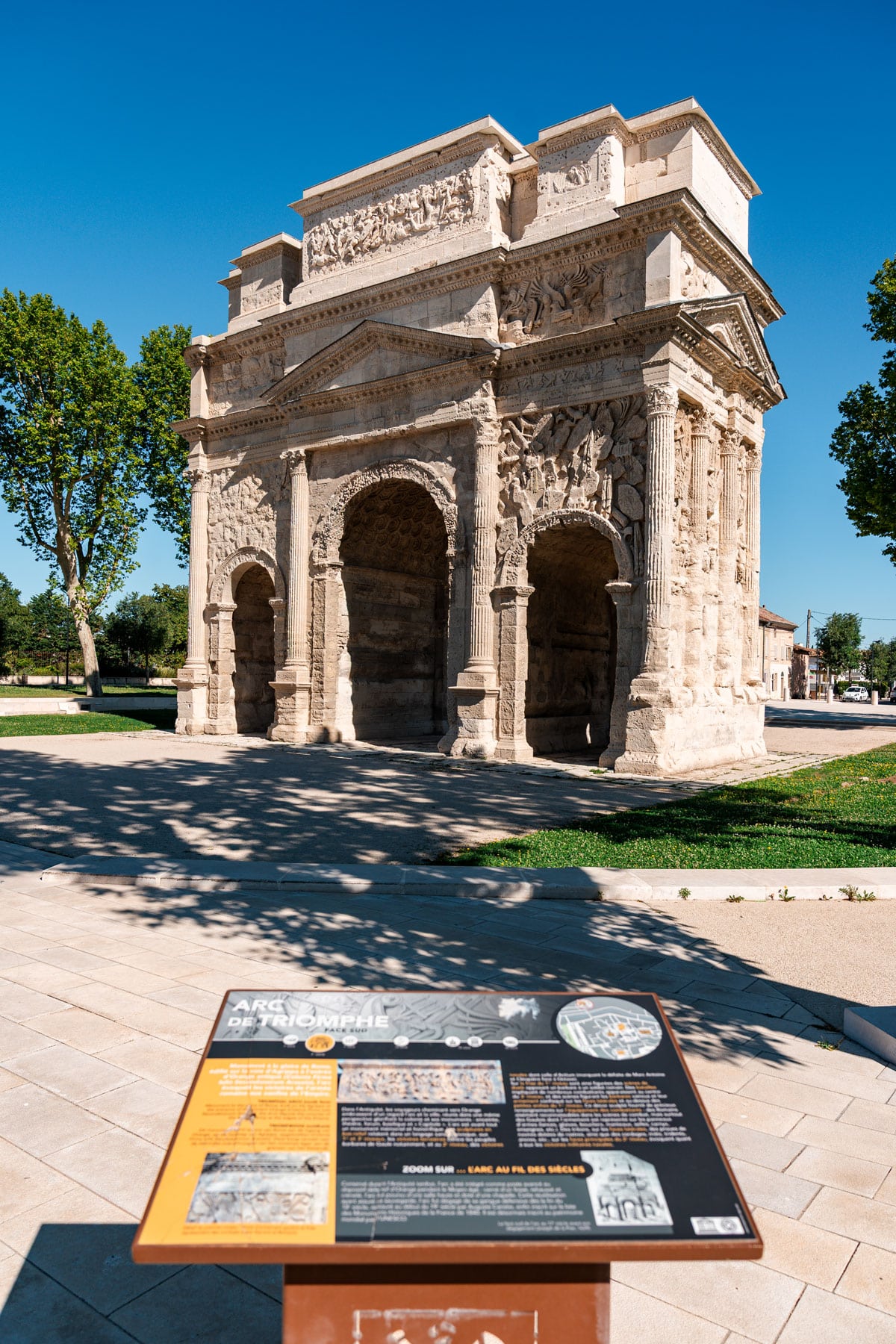 Triumphal Arch in Orange, France with an information board in front.