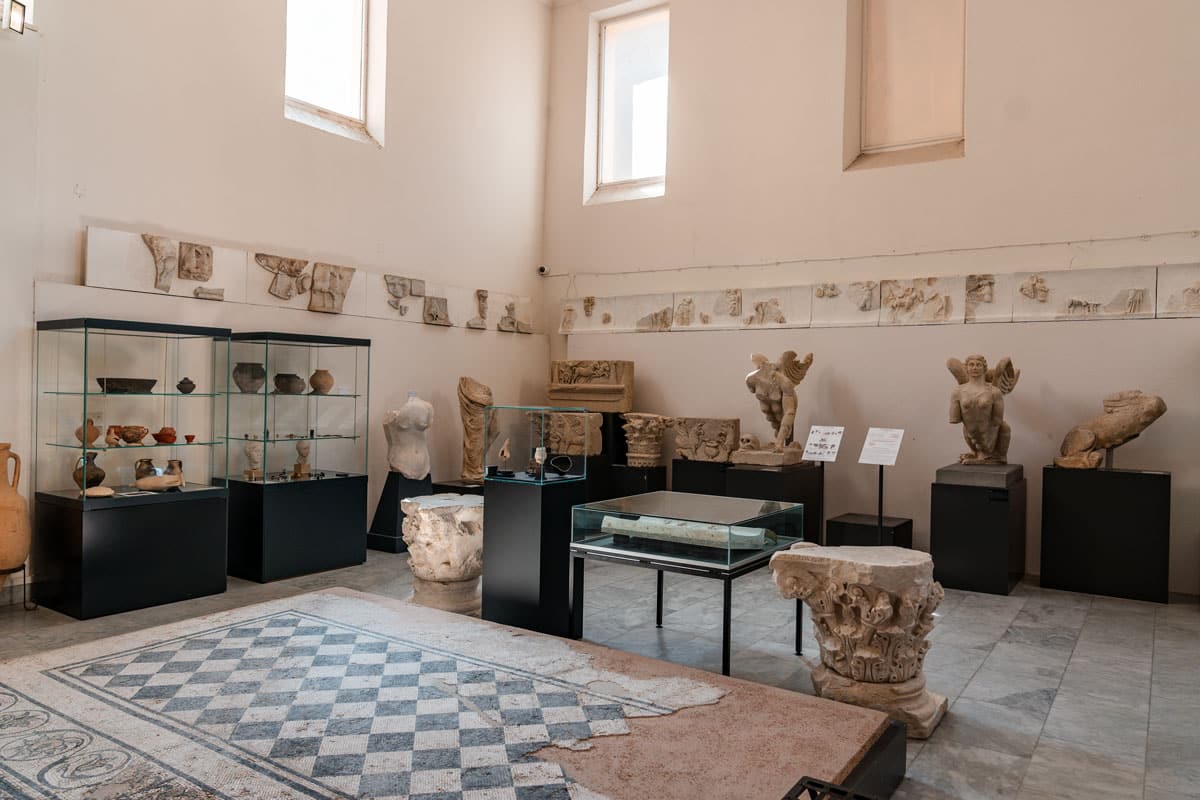 A display room with Roman fragments, sculptures and cases set around a mosaic floor.