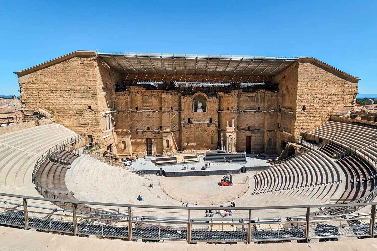 A wide view of the theatre with the stage being set up for a summer event, equipment and a forklift on the floor.