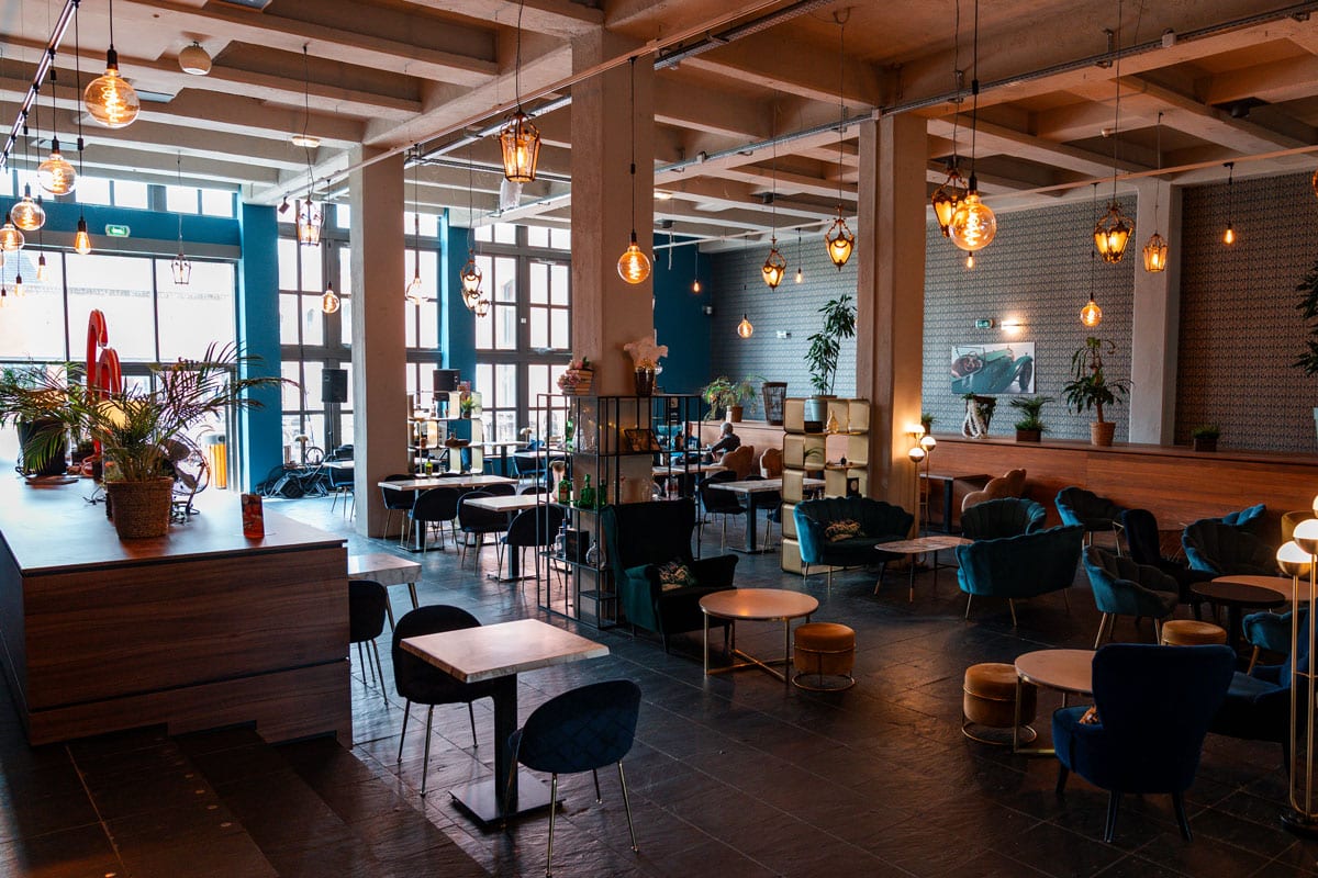 Le Gatsby bar with velvet armchairs, small tables and hanging bulb lights.
