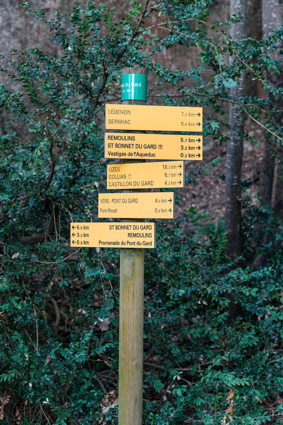 Yellow footpath sign near Pont du Gard showing distances to Collias and nearby villages.